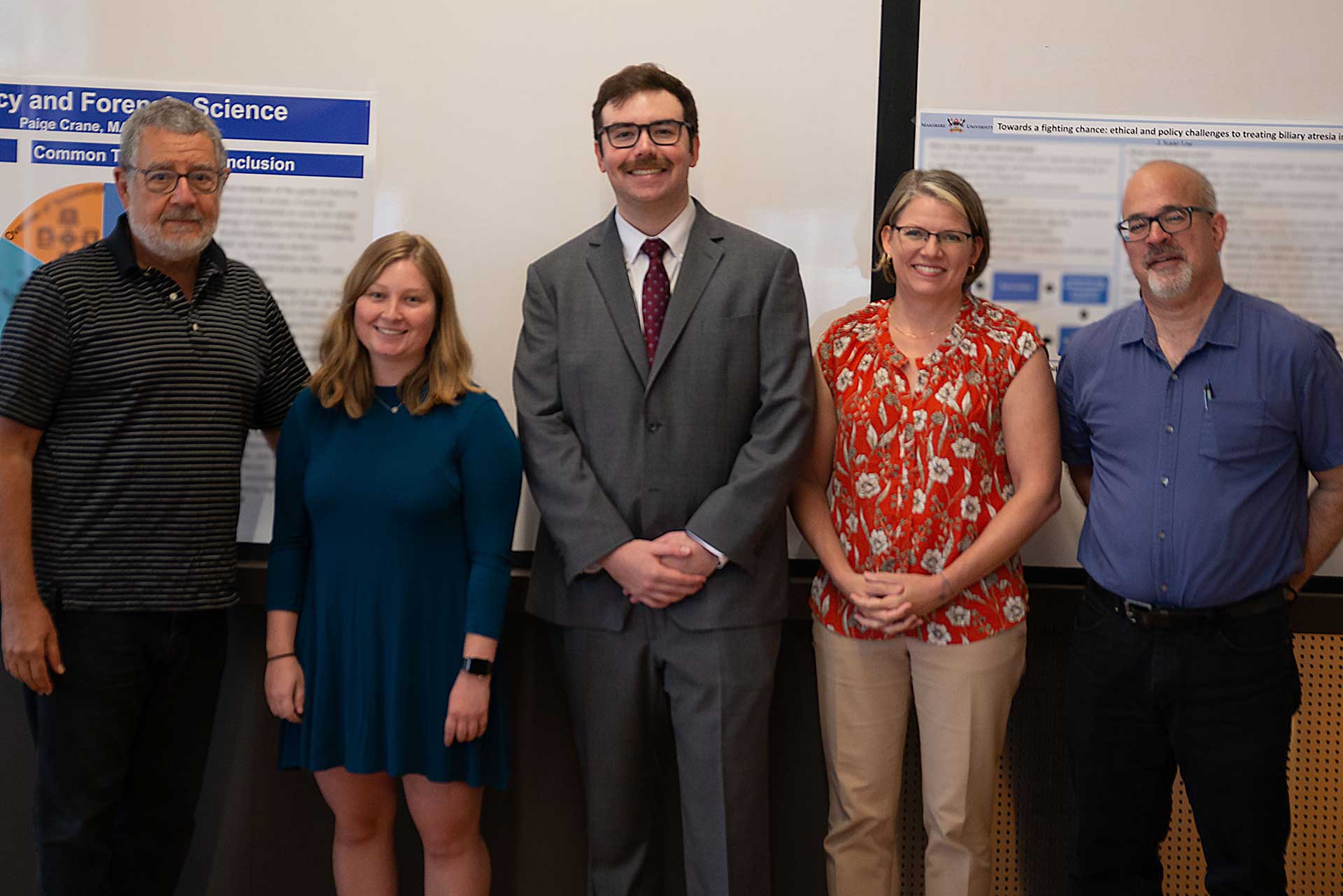 Paige Crane and Isaac Loy pose with Duke professors during their final practicum poster presentation