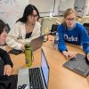 Three Duke students collaborate over a laptop.